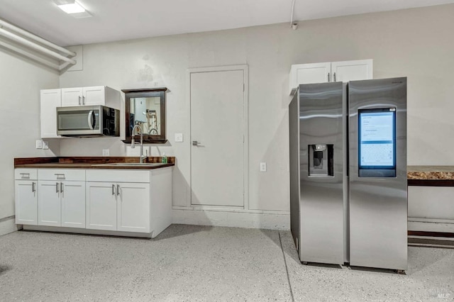 kitchen with dark countertops, appliances with stainless steel finishes, white cabinetry, and a sink