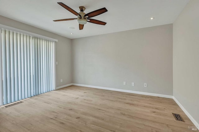 spare room featuring visible vents, a ceiling fan, baseboards, and wood finished floors