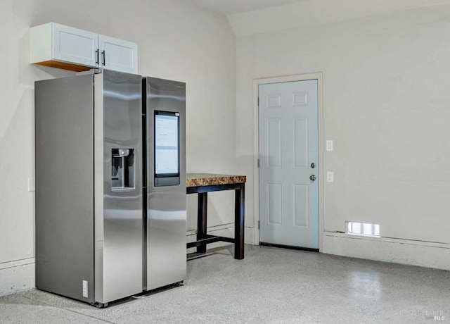 kitchen featuring visible vents, light speckled floor, white cabinets, stainless steel fridge with ice dispenser, and vaulted ceiling