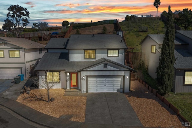 view of front of house with concrete driveway, an attached garage, and roof with shingles