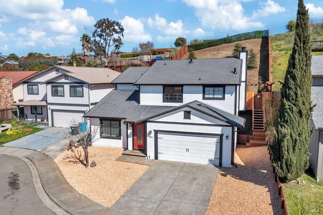 traditional-style home with a shingled roof, stairway, a residential view, concrete driveway, and a chimney