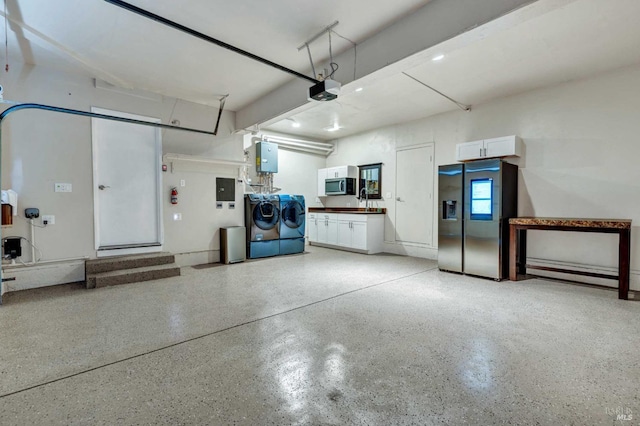 garage featuring baseboard heating, independent washer and dryer, a garage door opener, and stainless steel refrigerator with ice dispenser