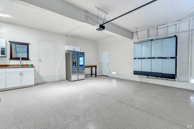 garage with a sink, a garage door opener, and stainless steel fridge with ice dispenser