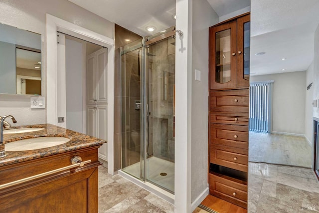 full bath featuring baseboards, a stall shower, and vanity