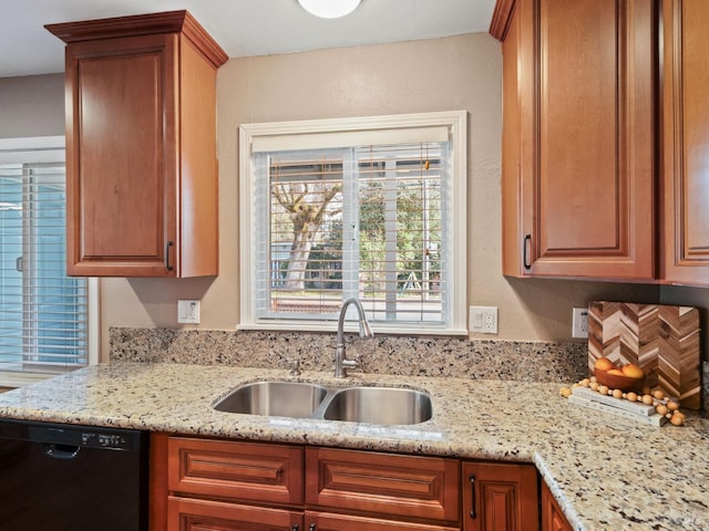 kitchen with a sink, light stone countertops, brown cabinetry, and dishwasher