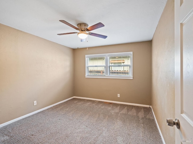 carpeted spare room featuring baseboards and a ceiling fan