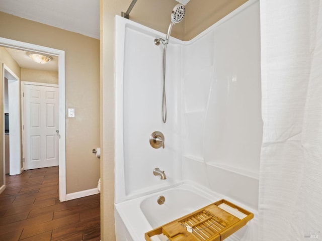 full bath featuring baseboards, shower / bathtub combination, and wood finished floors