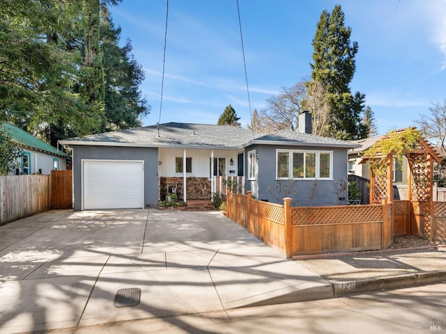 single story home featuring an attached garage, a fenced front yard, and concrete driveway