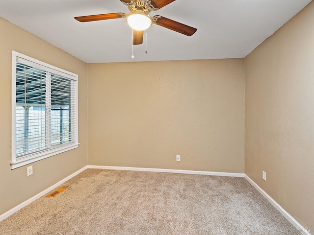 carpeted spare room featuring visible vents, ceiling fan, and baseboards