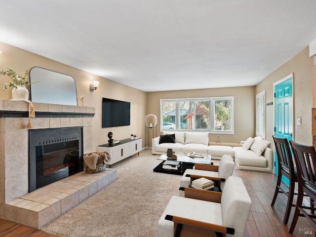 living area featuring a tiled fireplace and wood finished floors