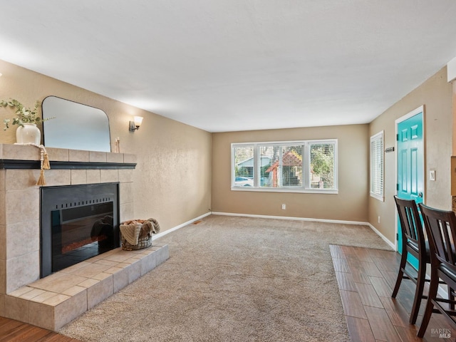 living room featuring carpet flooring, baseboards, and a tiled fireplace