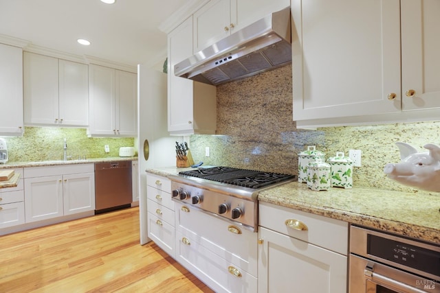 kitchen featuring white cabinets, light wood-style flooring, appliances with stainless steel finishes, under cabinet range hood, and a sink