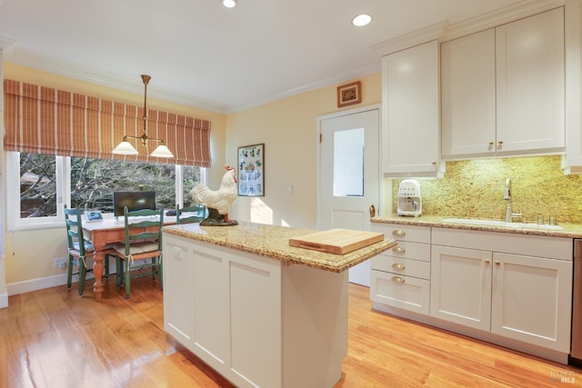 kitchen with a center island, a sink, light wood-style flooring, and crown molding