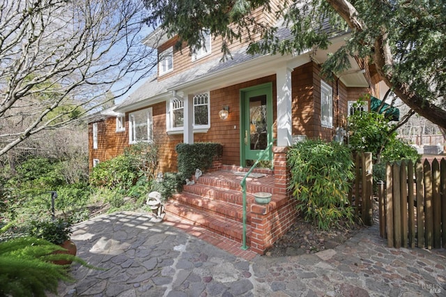 property entrance featuring fence and roof with shingles