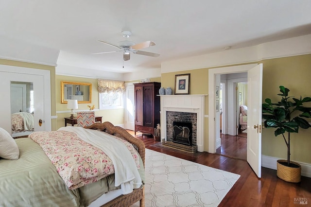 bedroom featuring a ceiling fan, a fireplace with flush hearth, baseboards, and dark wood-style flooring