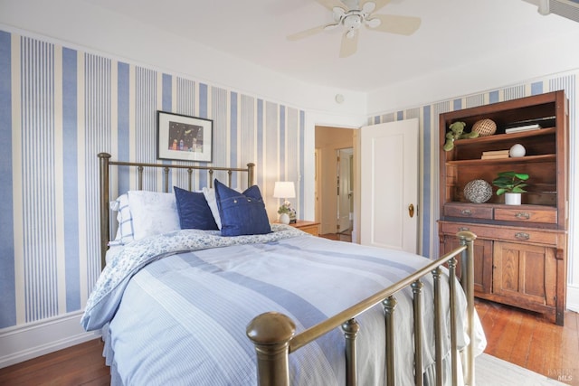 bedroom with wallpapered walls, ceiling fan, and wood finished floors