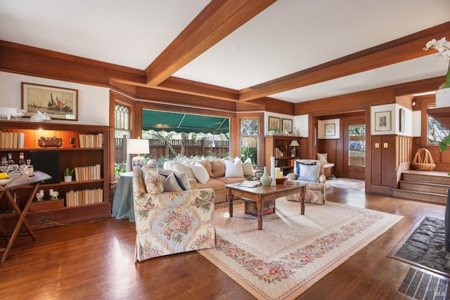 living room with beam ceiling, wood walls, stairway, and wood finished floors