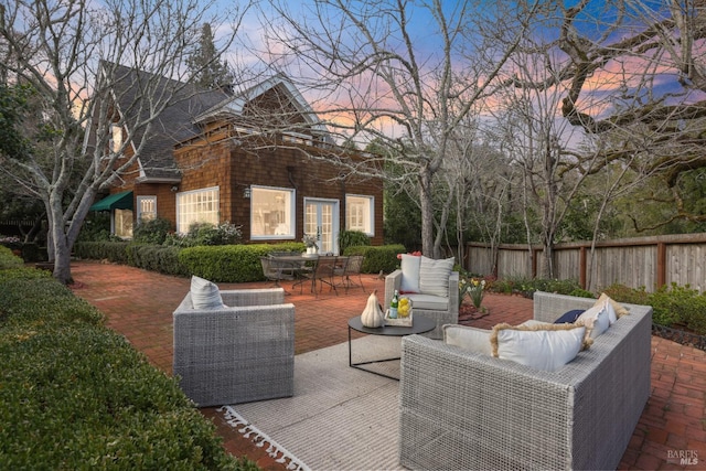 patio terrace at dusk with outdoor dining area, outdoor lounge area, and fence