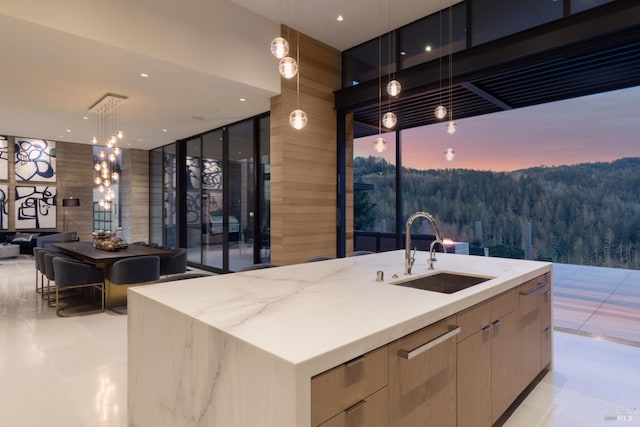 bar with expansive windows, pendant lighting, a sink, and a wooded view