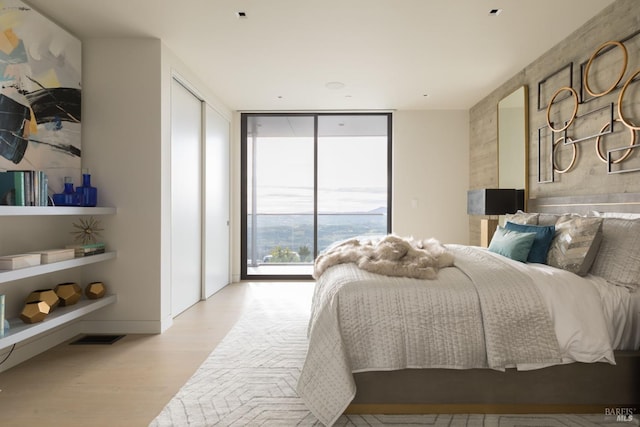 bedroom featuring expansive windows, access to outside, wood finished floors, and visible vents