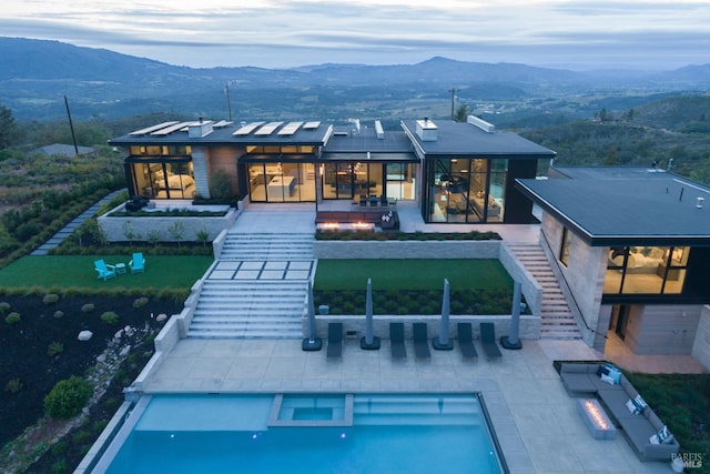 back of house with a pool with connected hot tub, stairway, a patio area, and a mountain view