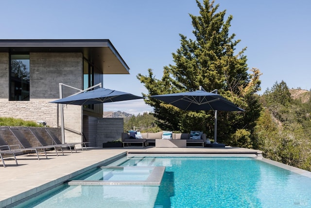 view of swimming pool featuring a pool with connected hot tub, a patio, and an outdoor living space