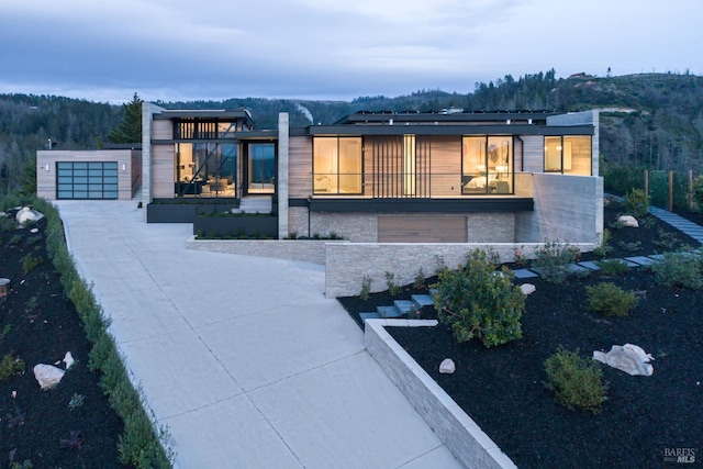 exterior space with a garage, stone siding, and a forest view