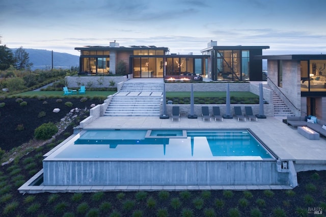 back of property with a patio, a mountain view, outdoor lounge area, a pool with connected hot tub, and stairway