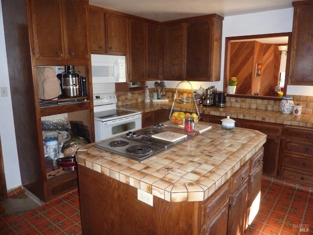 kitchen featuring tile countertops, white appliances, a kitchen island, and decorative backsplash