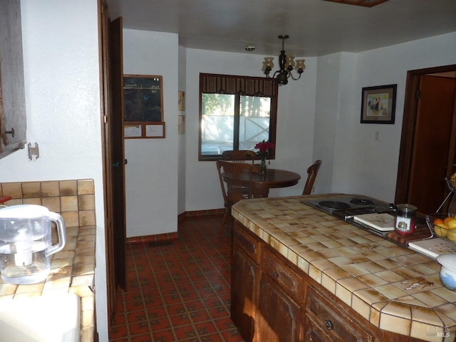 kitchen with tile countertops, baseboards, and a notable chandelier