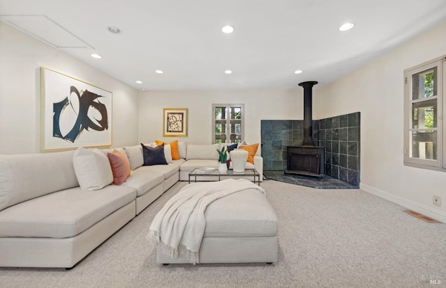 living area featuring baseboards, visible vents, a wood stove, carpet flooring, and recessed lighting