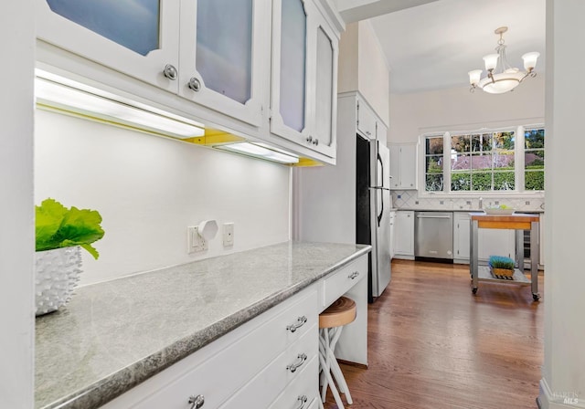 kitchen featuring stainless steel appliances, decorative backsplash, white cabinets, wood finished floors, and beverage cooler