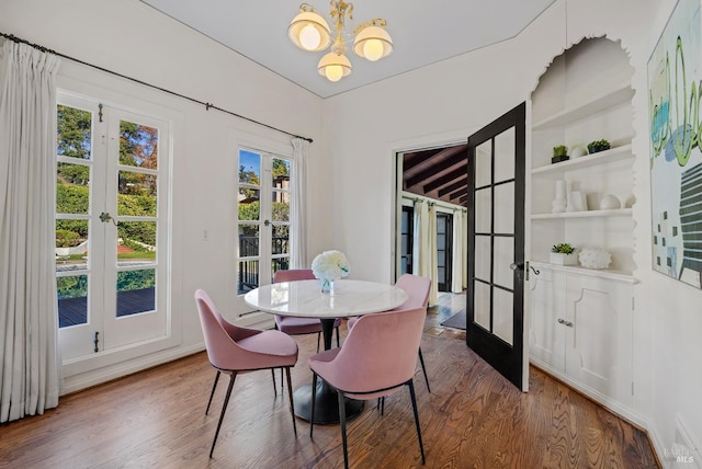 dining space with a chandelier, french doors, and wood finished floors