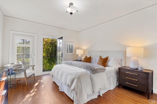 bedroom with access to outside, baseboards, and wood finished floors