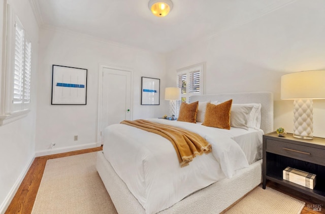 bedroom with baseboards, wood finished floors, and ornamental molding