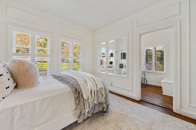 bedroom featuring baseboards, wood finished floors, and a decorative wall