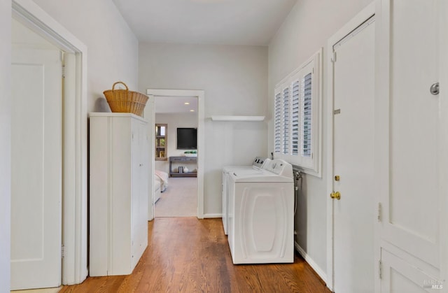 laundry room featuring laundry area, washer and clothes dryer, baseboards, and wood finished floors