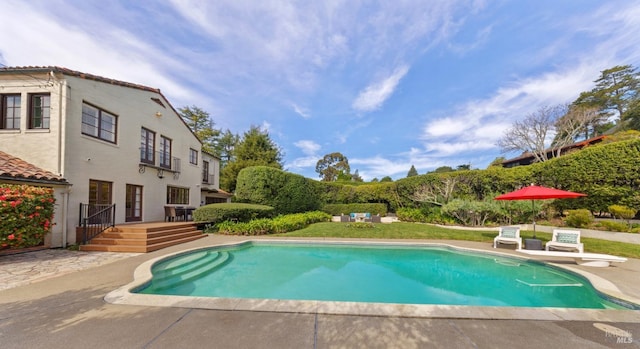 pool with a patio area, a deck, and a diving board