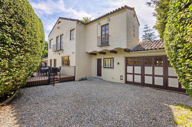 back of property with an attached garage, a tiled roof, and stucco siding