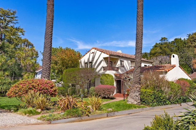 view of front of house with a balcony, a tile roof, and stucco siding