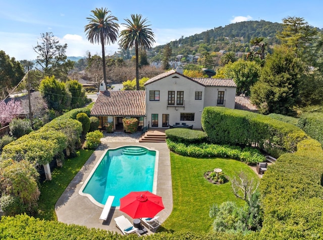 outdoor pool featuring a mountain view, a diving board, and a yard