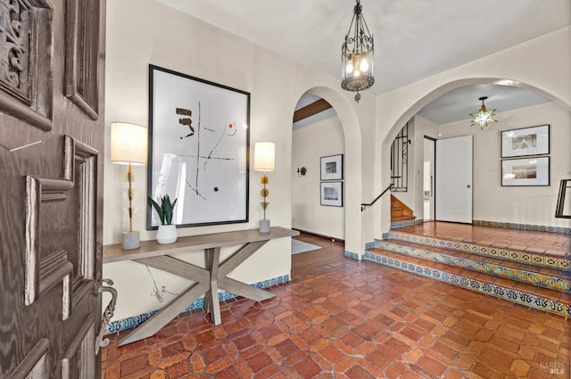 entryway with stairway, baseboards, and ceiling fan with notable chandelier