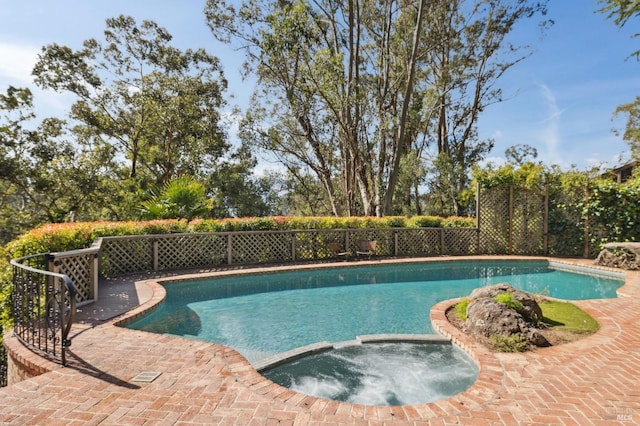 view of swimming pool with a pool with connected hot tub and fence