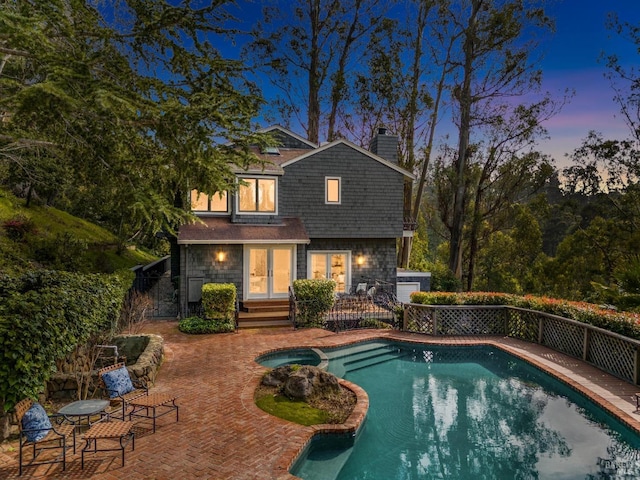 view of swimming pool featuring a patio, fence, and a pool with connected hot tub