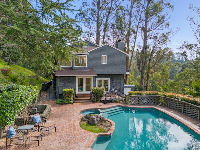 view of pool featuring a pool with connected hot tub, french doors, a patio area, and fence