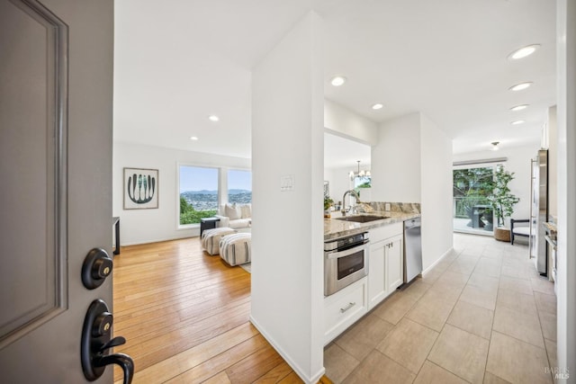 kitchen with plenty of natural light, light stone counters, stainless steel appliances, and a sink