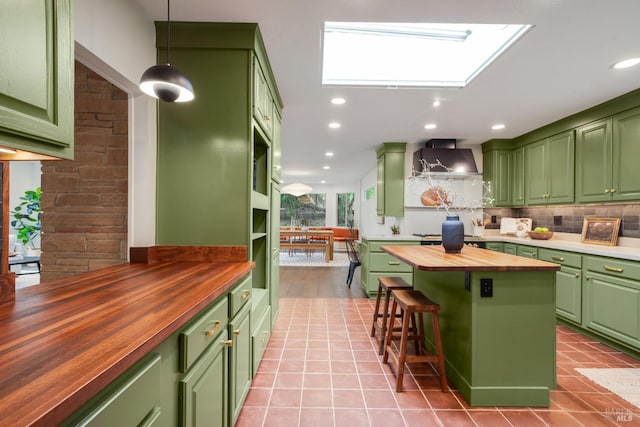 kitchen featuring wall chimney exhaust hood, backsplash, green cabinets, wooden counters, and light tile patterned flooring