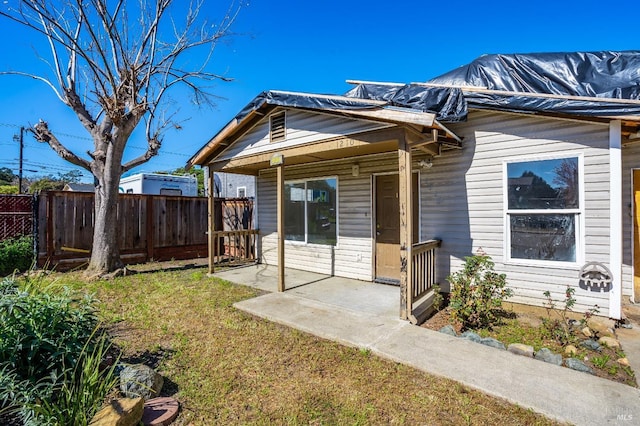 view of front of property with a patio area, fence, and a front yard