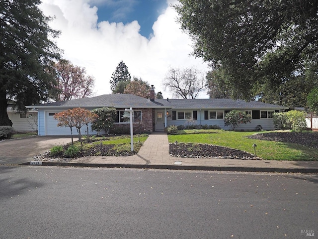 ranch-style house featuring a garage, driveway, a chimney, and a front lawn