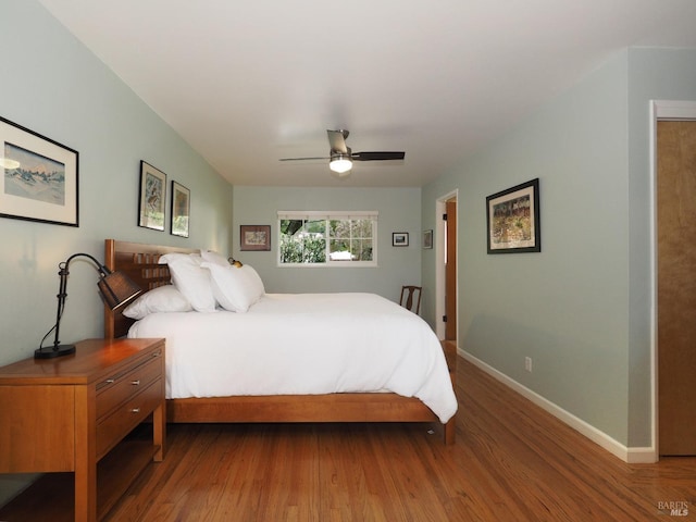 bedroom with a ceiling fan, baseboards, and wood finished floors